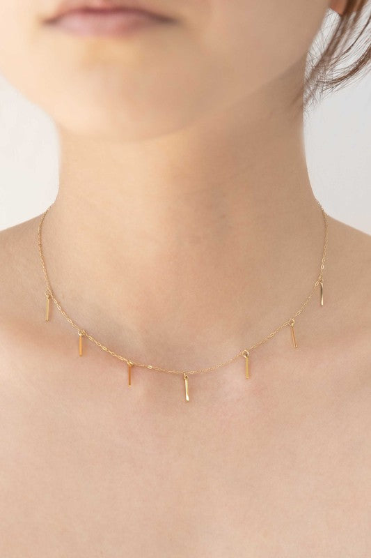 Gold necklace with a sleek chain, seven delicate gold charms, and an adjustable 14-inch length with a 2.5-inch extension.