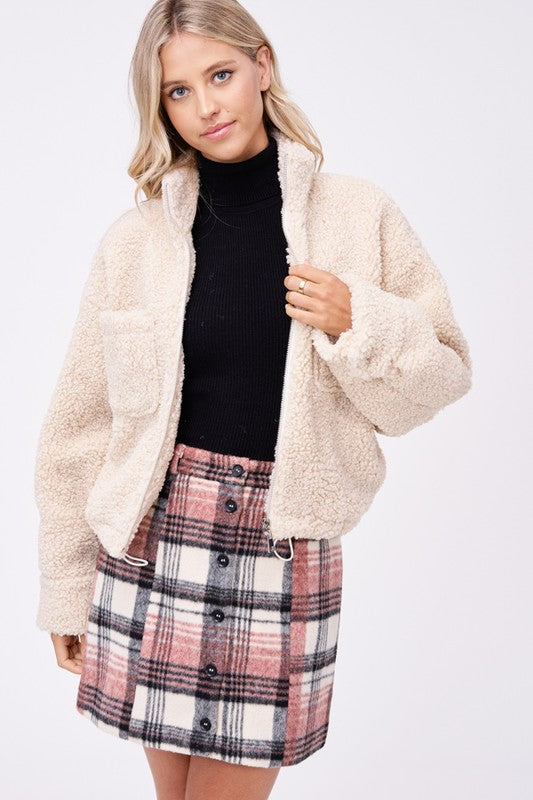 Front view of cream sherpa jacket with zip closure and chest pockets