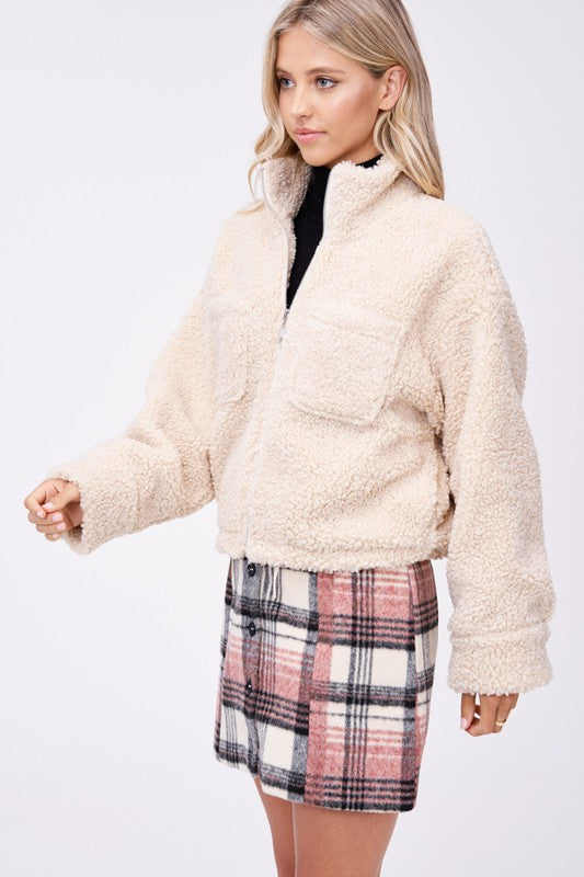 Side angle of cream sherpa jacket with zip closure and cozy fabric