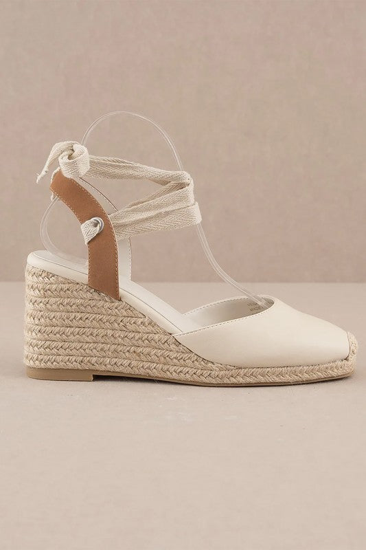 Beige espadrille wedge sandals featuring a lace-up design.