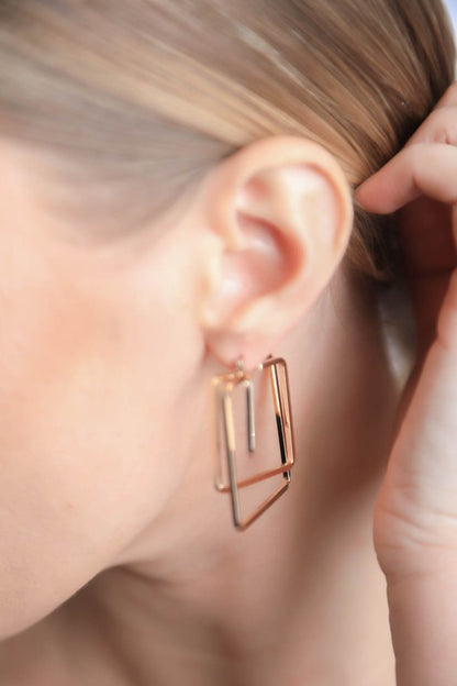 Model wearing Minimal Gold Square Cut Out Earrings with geometric design, moving joint, and latch stud closure.