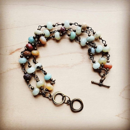 A handcrafted triple-strand bracelet featuring vibrant turquoise Amazonite stones, creating a layered, textured look. Adjustable to two wrist sizes, measuring 7.5" in length, each piece is unique.