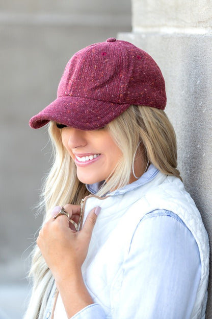 Woman wearing Faryn Fall Tweed Ball Cap in Cranberry with fall-ready texture and adjustable clasp