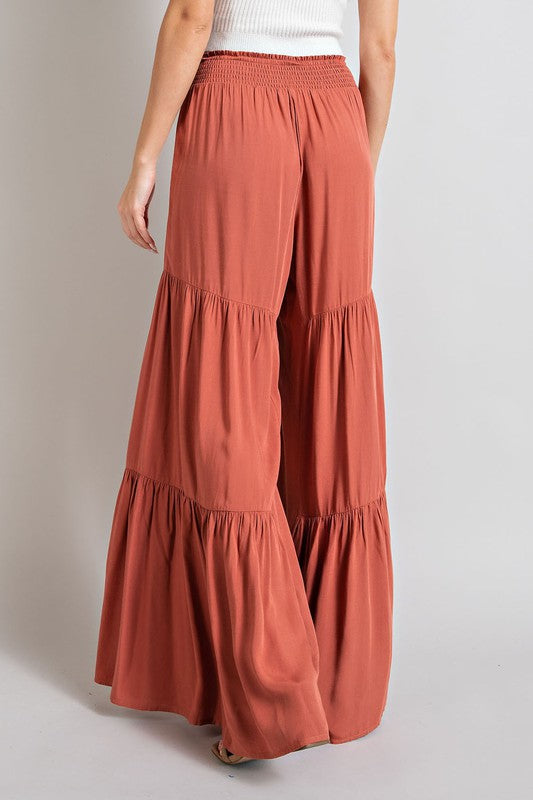 Terracotta wide-leg, tiered pants with a smocked waist and tie front, offering a comfortable, oversized fit for a relaxed, casual look.