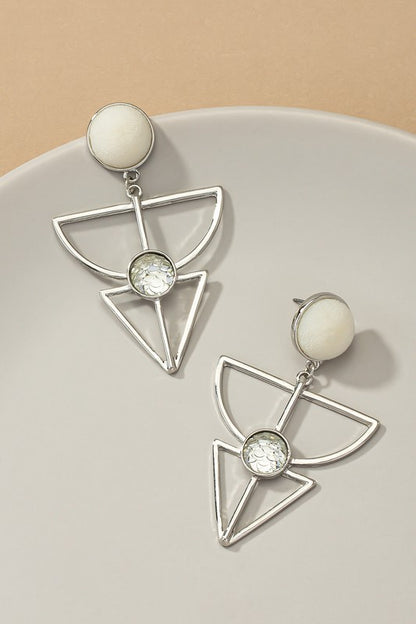 Silver earrings feature a velvet stud, geometric cutout design, and a textured white stone embedded in the cutout. They are 2.5 inches long.