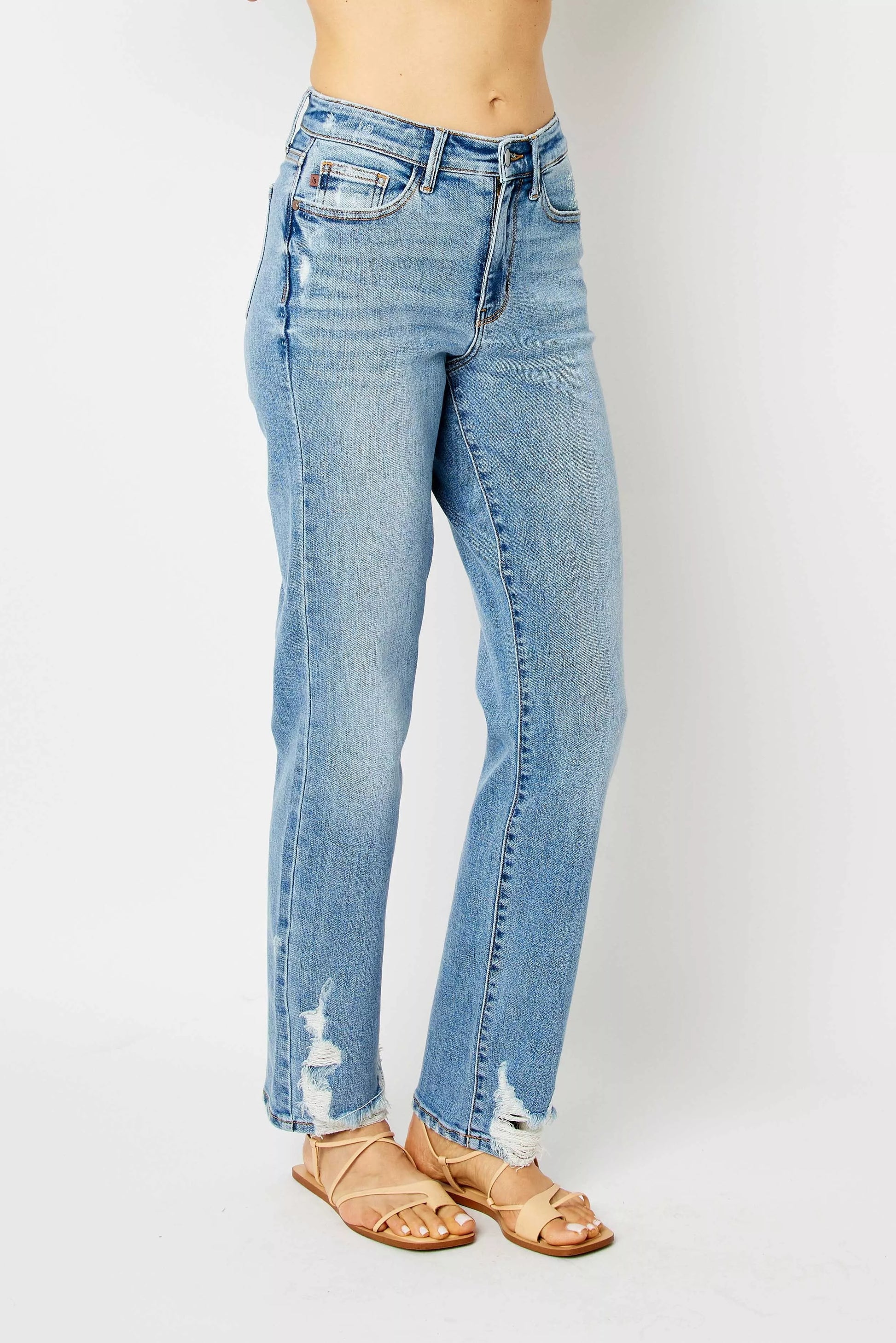 Angled view of size inclusive Estee medium wash distressed high waist straight jeans.