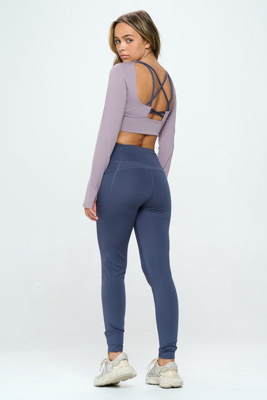 Mauve two-piece activewear set featuring a cropped top with strap details, long sleeves, and a round neckline, paired with high-waisted, long bottoms.