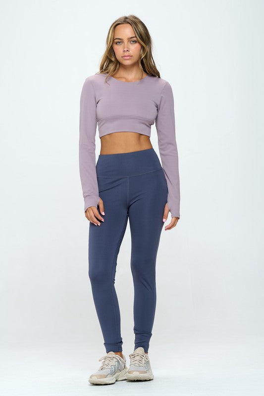 Mauve two-piece activewear set featuring a cropped top with strap details, long sleeves, and a round neckline, paired with high-waisted, long bottoms.