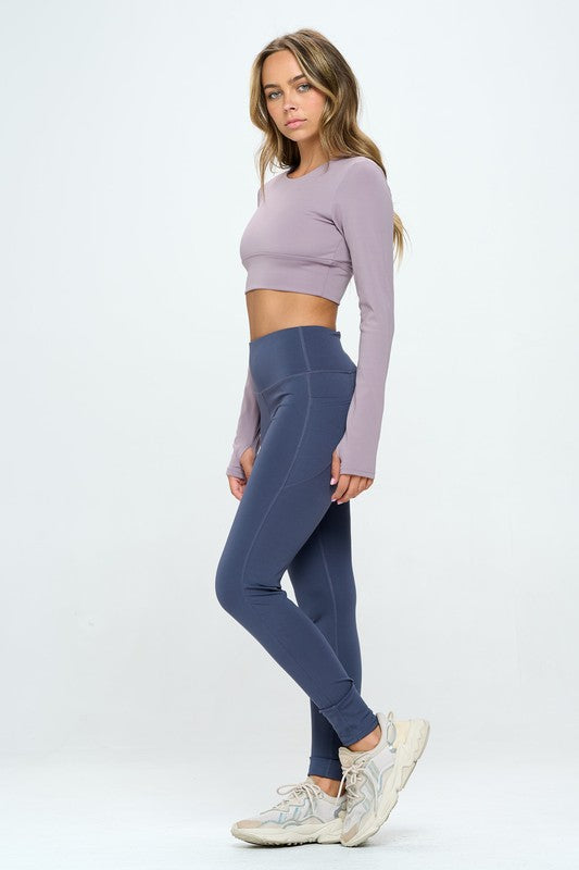 Mauve two-piece activewear set featuring a cropped top with strap details, long sleeves, and a round neckline, paired with high-waisted, long bottoms.