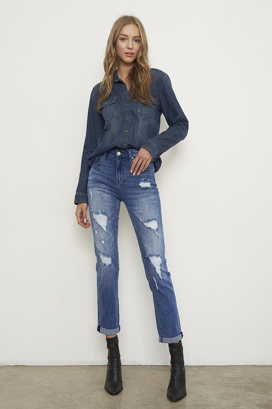 Medium wash distressed girlfriend jeans with a slim fit, mid-rise waist, button closure, and ankle-length cut.