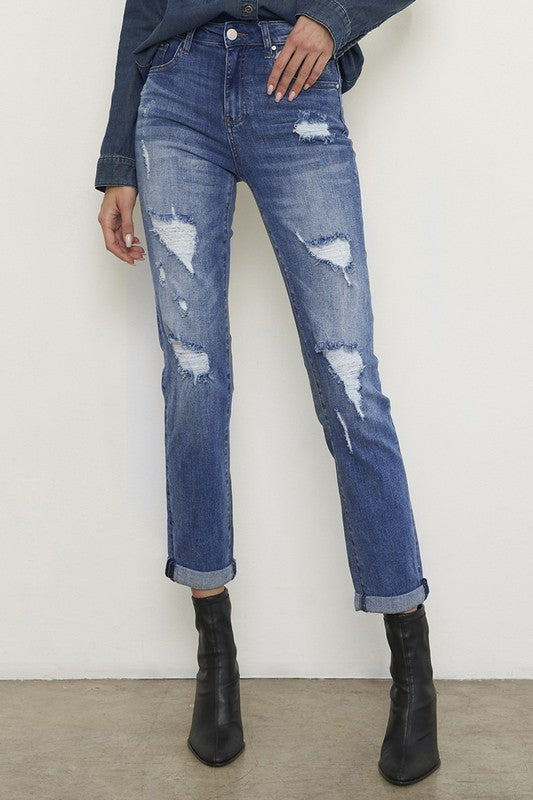 Medium wash distressed girlfriend jeans with a slim fit, mid-rise waist, button closure, and ankle-length cut.