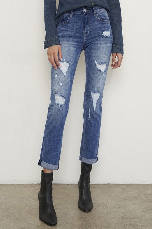 Medium wash distressed girlfriend jeans with a slim fit, mid-rise waist, button closure, and ankle-length cut.