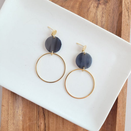 Flat lay of Sadie Earrings in black with 18k gold-plated charm and acrylic accents.