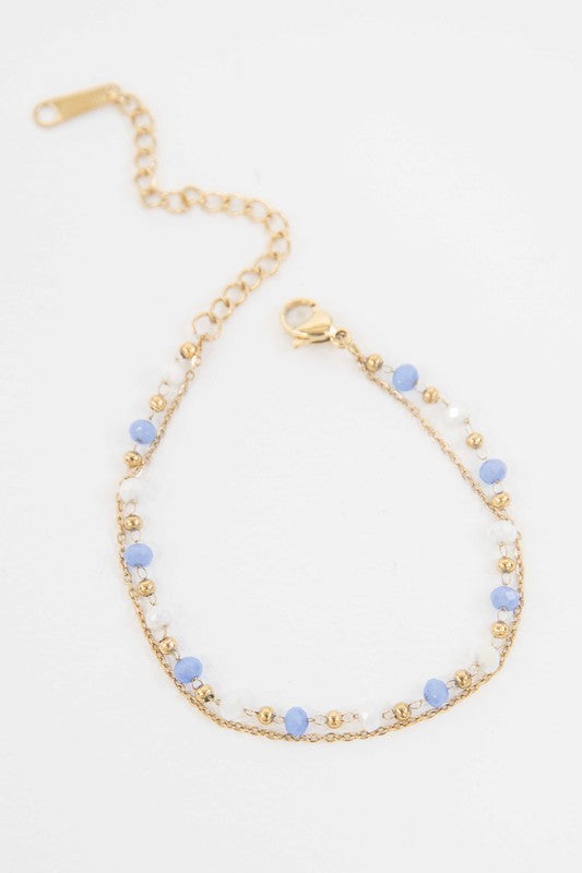 Double-layered Cana beaded bracelet with vibrant blue and white beads and a delicate gold-plated chain.