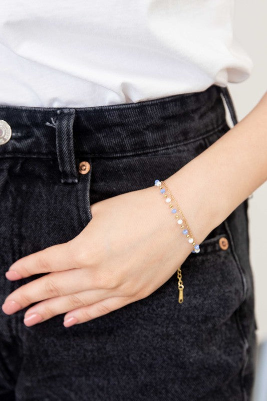 Double-layered Cana beaded bracelet with vibrant blue and white beads and a delicate gold-plated chain.