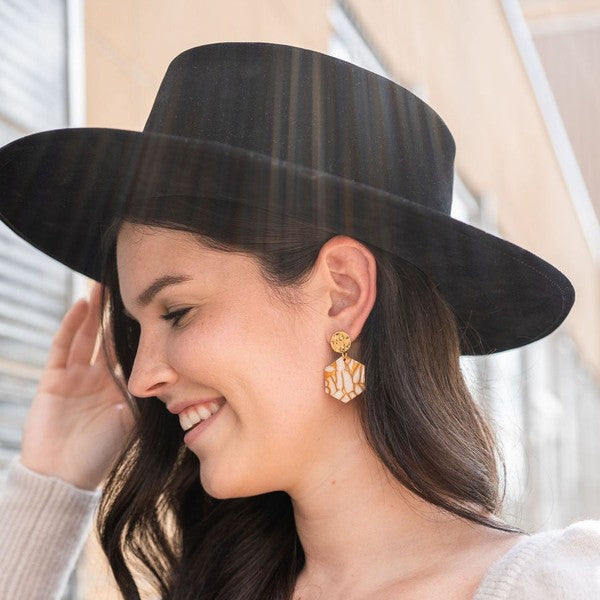 Woman wearing Roxy Hexagon Earrings in pumpkin spice, showing hexagon shape and warm autumn hue.