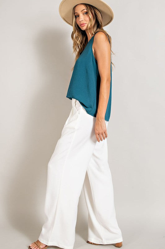 Off white, straight-leg pants with pleats, pockets, and a zip fly, with a relaxed, loose fit.