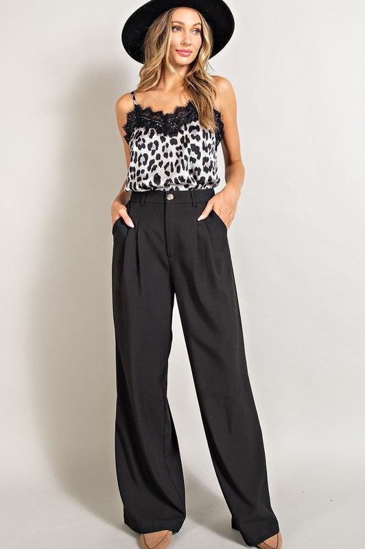 Black, straight-leg pants with pleats, pockets, and a zip fly, with a relaxed, loose fit.