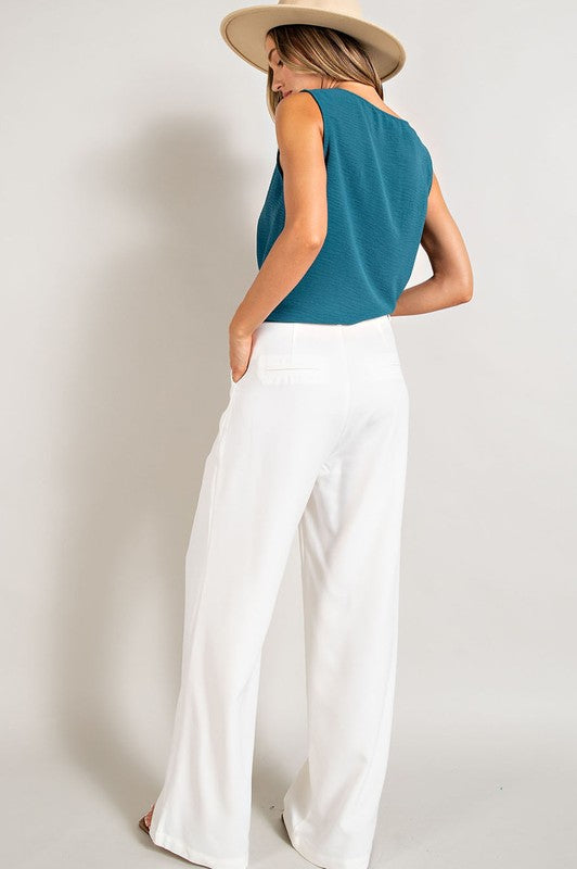 Off white, straight-leg pants with pleats, pockets, and a zip fly, with a relaxed, loose fit.