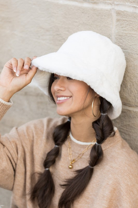 Side angle of woman wearing Izzie Plush Bucket Hat in White, soft plush hat with wide brim