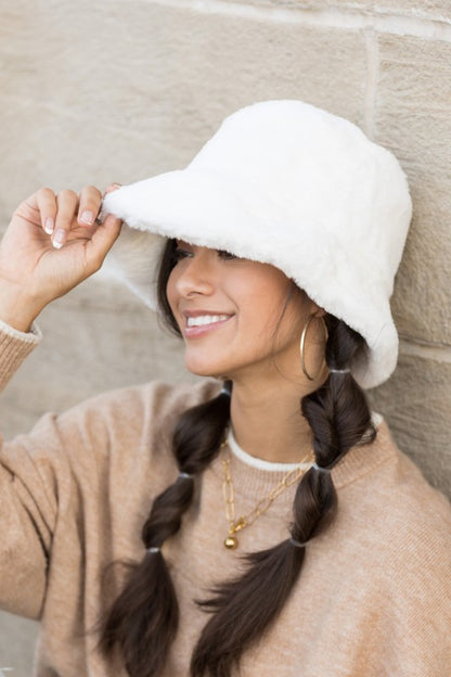 Side angle of woman wearing Izzie Plush Bucket Hat in White, soft plush hat with wide brim