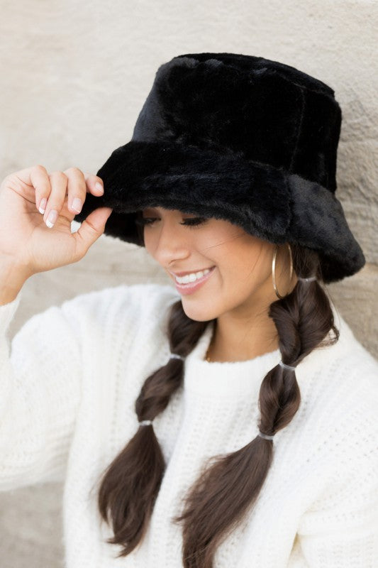 Side angle of woman wearing Izzie Plush Bucket Hat in Black, plush finish with wide brim