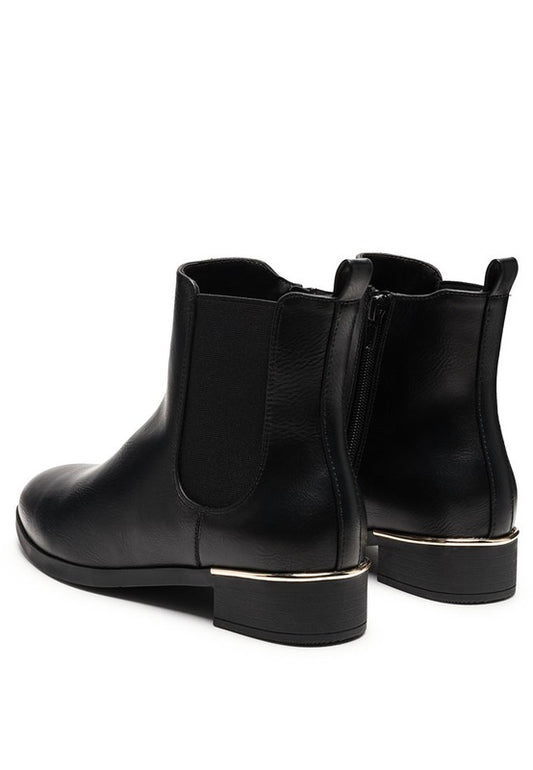 Back angled view of black Chelsea boots with gold detail on heel.