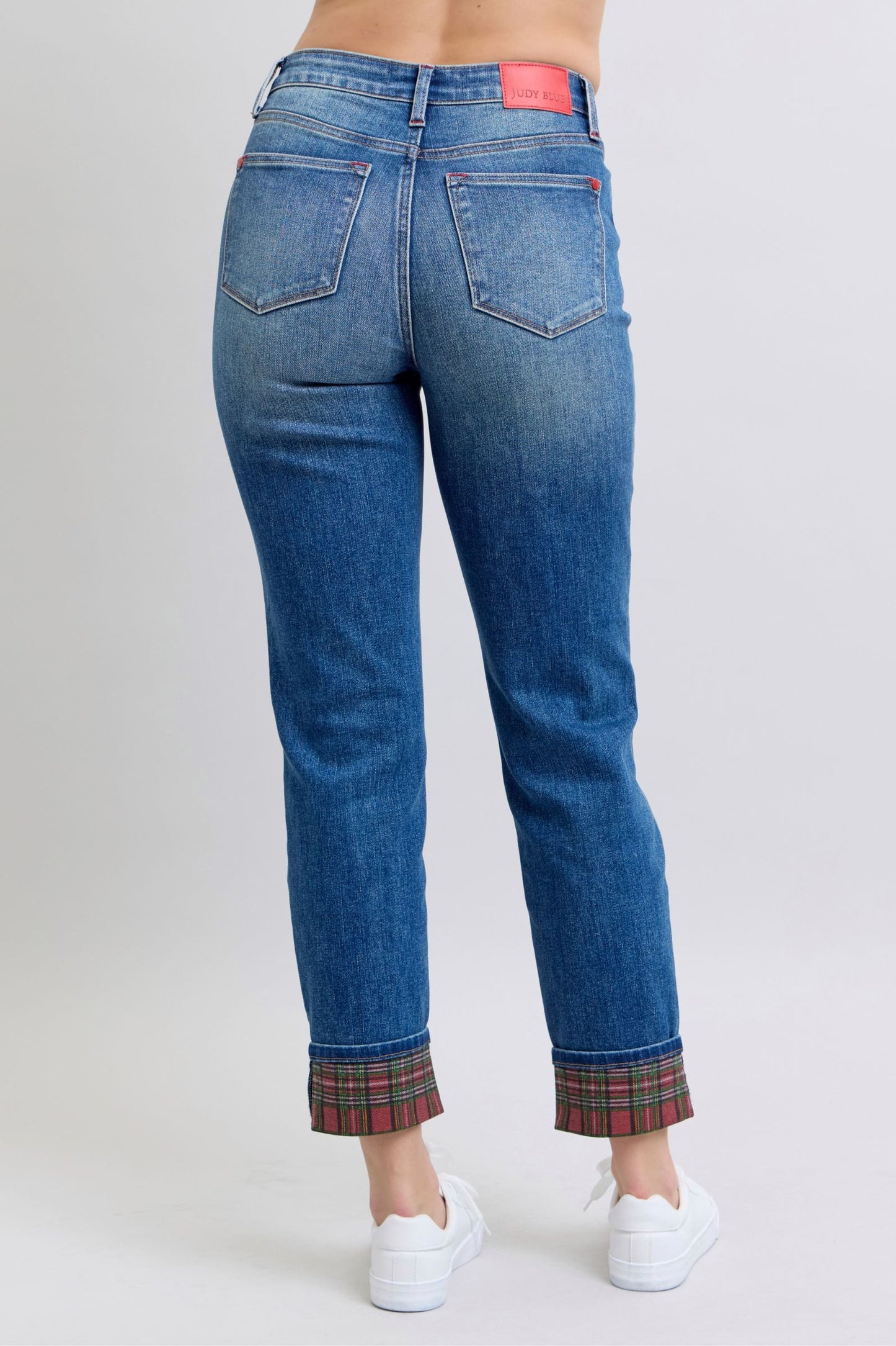 Women's mid rise, medium-wash straight-leg jeans with red and green plaid cuffs.