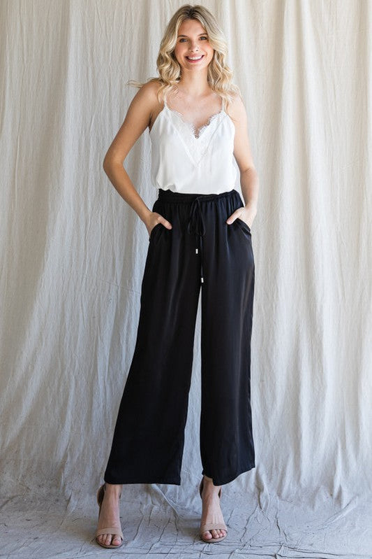 Model wearing Cita Wide Leg Bottoms in Black with high-waisted fit and flowy wide-leg silhouette.