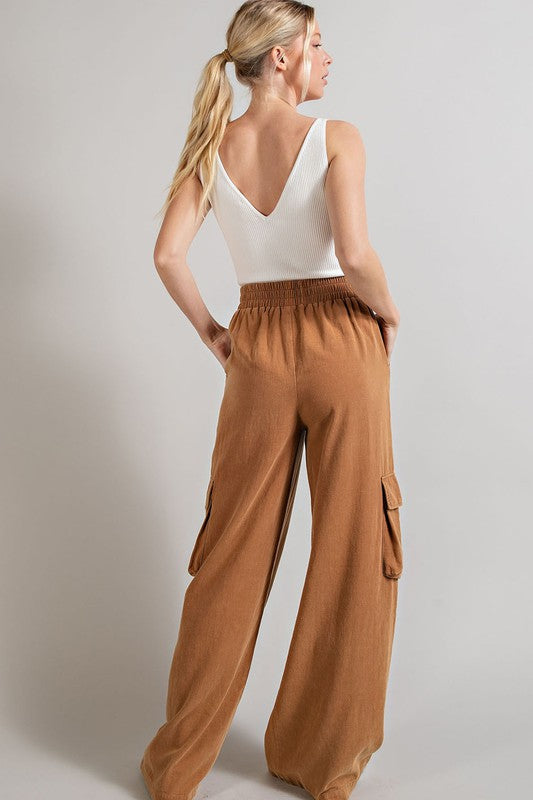 Wide-leg mineral-washed cargo pants in a clay color with an elastic waist and multiple pockets.