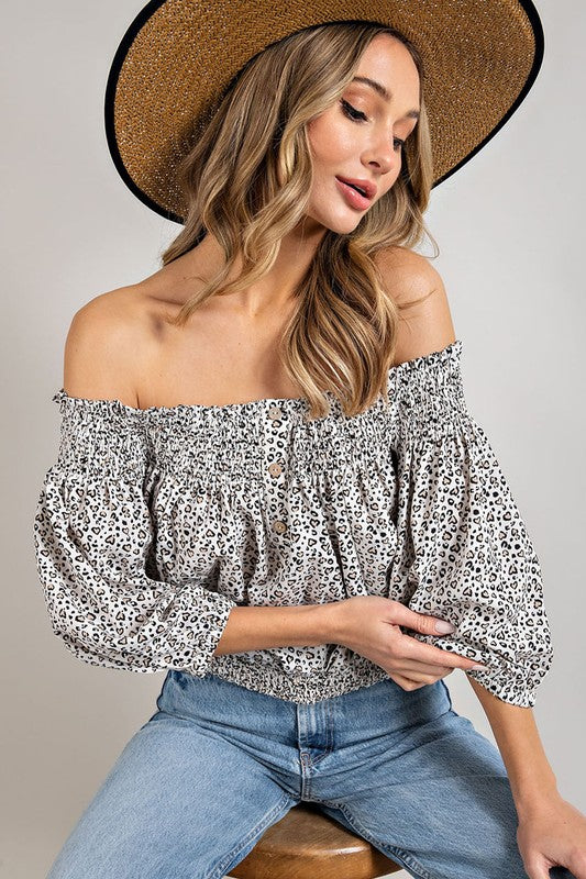 Off white animal print top with smocked off-the-shoulder neckline and button trim. Features a fitted and flared silhouette, 3/4 length puff sleeves, and a romantic, flirty style.