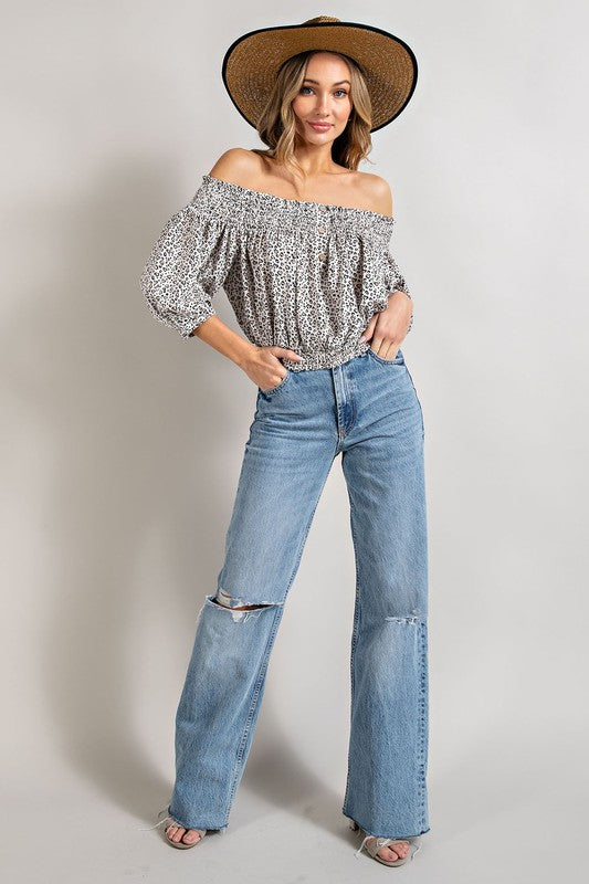 Off white animal print top with smocked off-the-shoulder neckline and button trim. Features a fitted and flared silhouette, 3/4 length puff sleeves, and a romantic, flirty style.