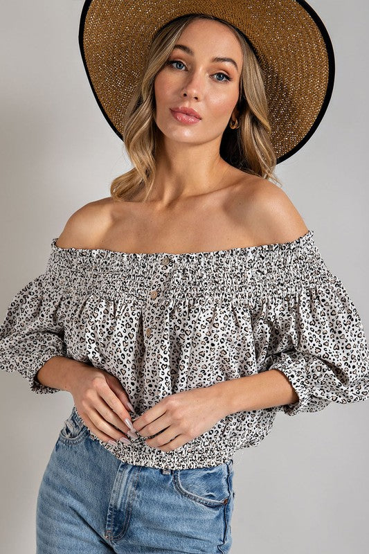 Off white animal print top with smocked off-the-shoulder neckline and button trim. Features a fitted and flared silhouette, 3/4 length puff sleeves, and a romantic, flirty style.