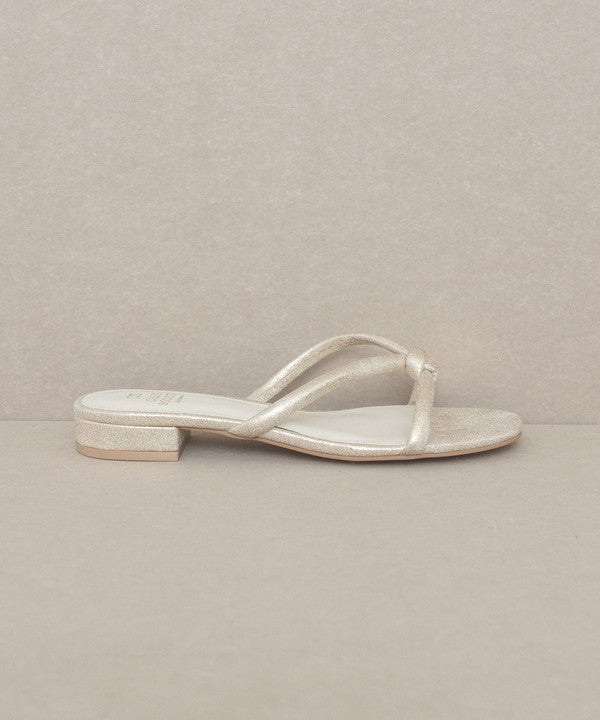 Knotted Flat Sandal in gold metallic features a minimalist design with a stylish knot detail. 