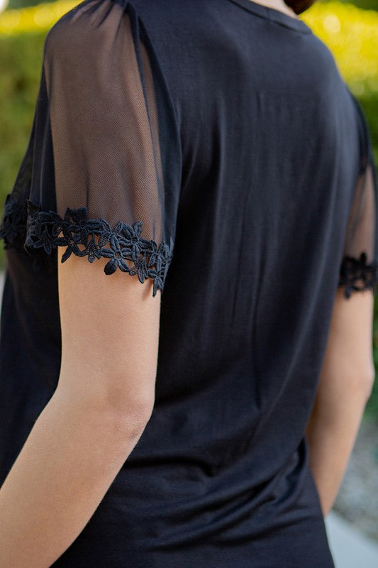 Black knit jersey top with short mesh flutter sleeves featuring floral lace trim, a loose fit, and a round neckline.