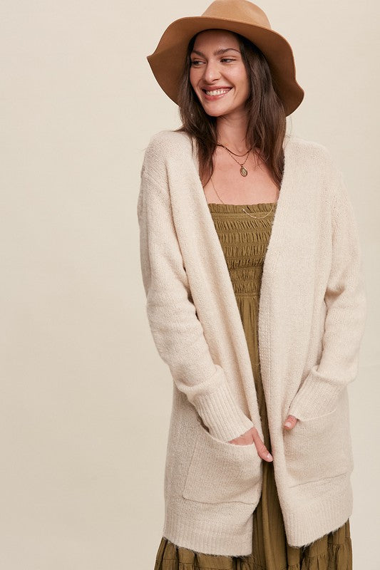 Cozy, natural solid-colored long knit cardigan with an open front, two functional pockets, and long sleeves.