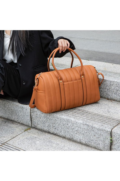 Luana Quilted Duffle Bag in Brown, woman seated holding bag by top handle.