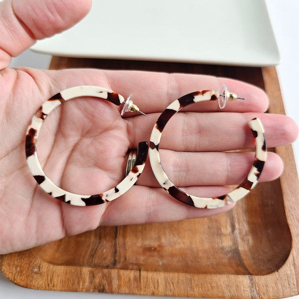 Cowhide patterned hoop earrings made from lightweight acrylic with a hypoallergenic stainless steel stud, 2" diameter.