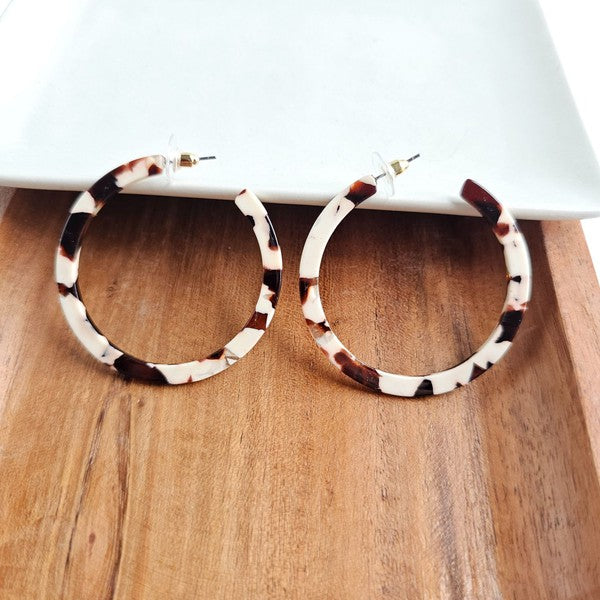 Cowhide patterned hoop earrings made from lightweight acrylic with a hypoallergenic stainless steel stud, 2" diameter.