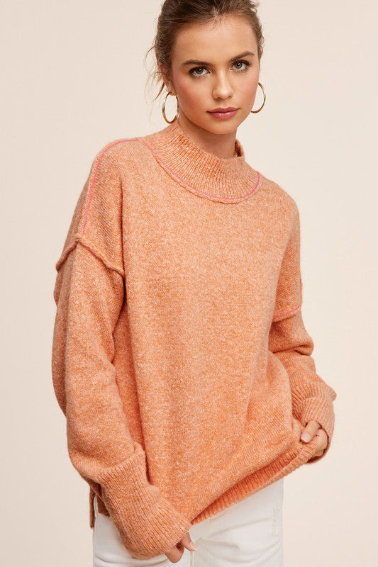 Cozy knit mock neck sweater in pumpkin, featuring long sleeves, drop shoulders, and an oversized fit.