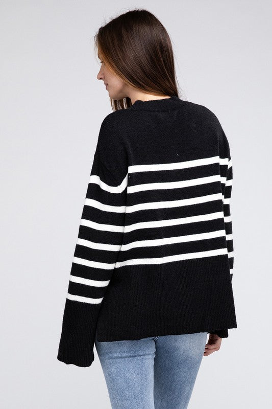 Black oversized sweater with a ribbed hem and striped pattern, featuring a round neckline and long sleeves.