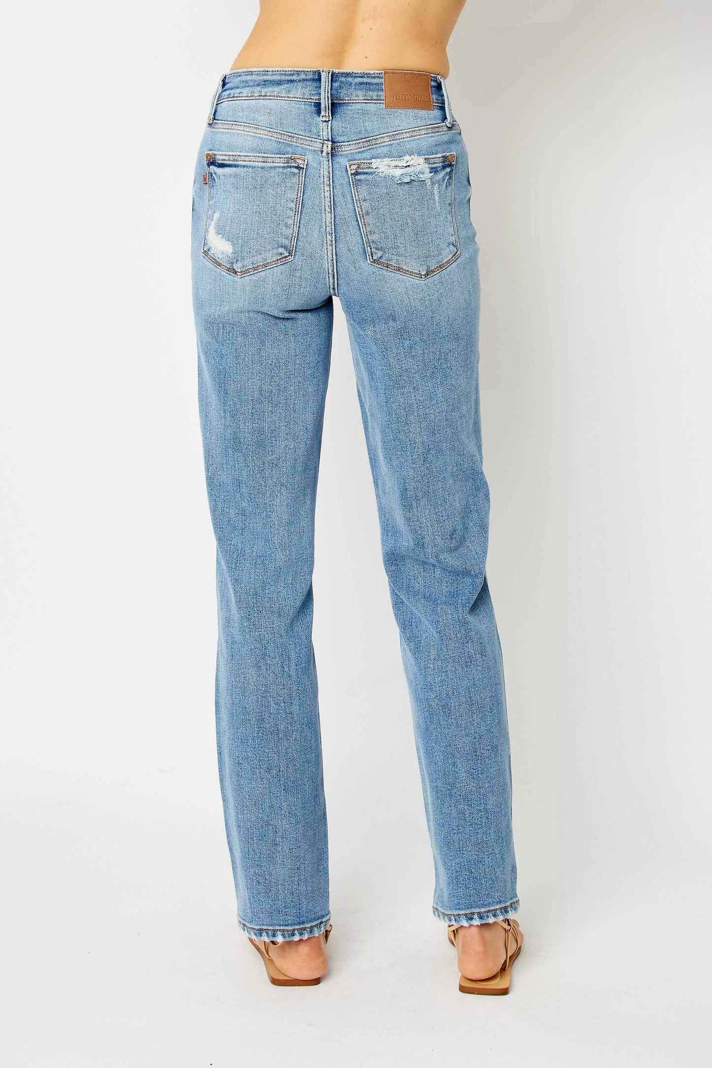 Back view size inclusive Estee Judy Blue jeans, medium wash straight cut with raw hem detail.