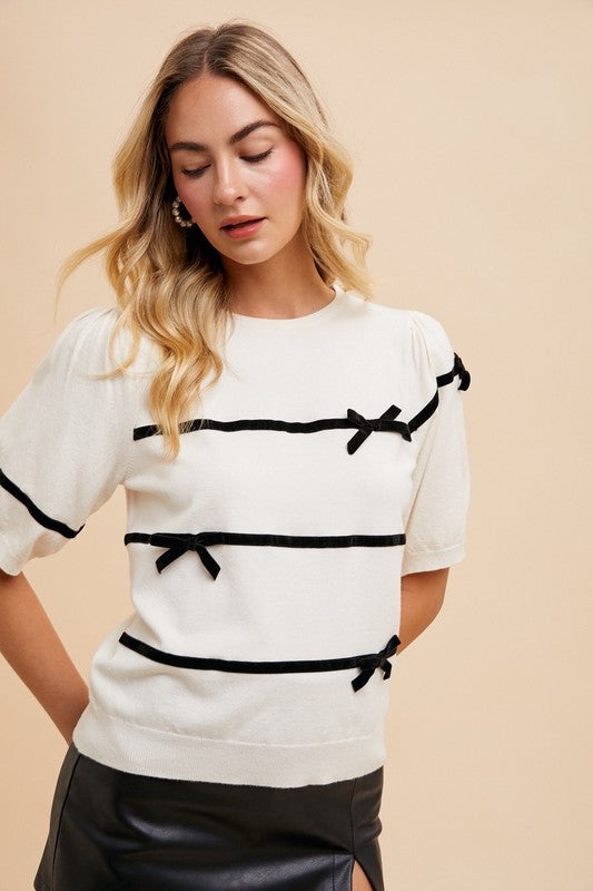 Bernadette Striped Bow Knit Top in white with black stripes, featuring feminine bow details, round neckline, short sleeves, and ribbed knit for a chic, comfortable style.