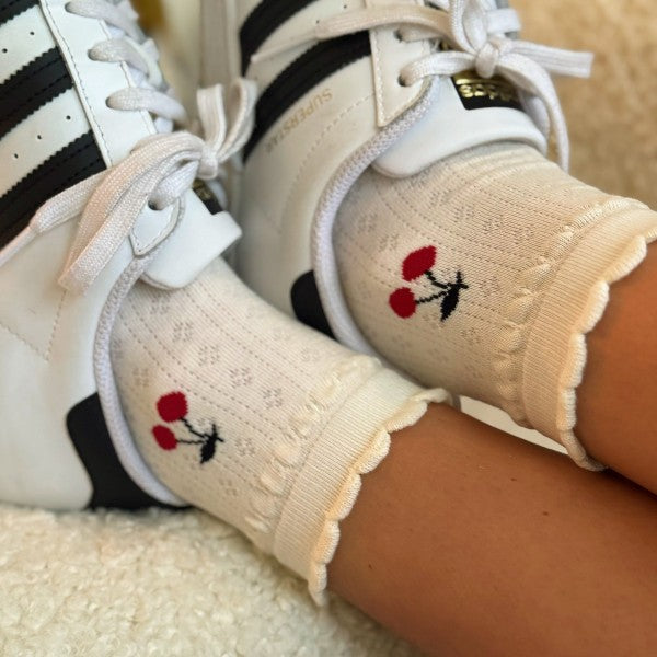 Woman wearing white cherry socks styled with sneakers.