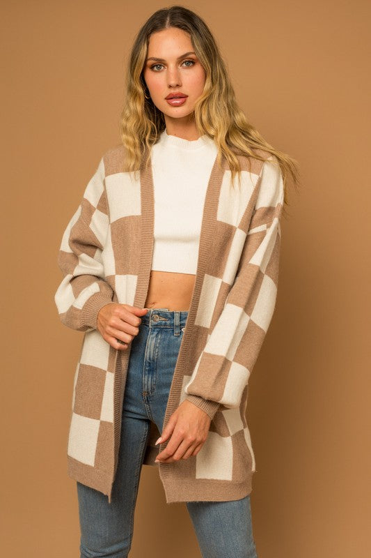 A long open-front cardigan made of knit fabric with a taupe and white checker pattern. It features long sleeves, side pockets, and a relaxed, medium long length