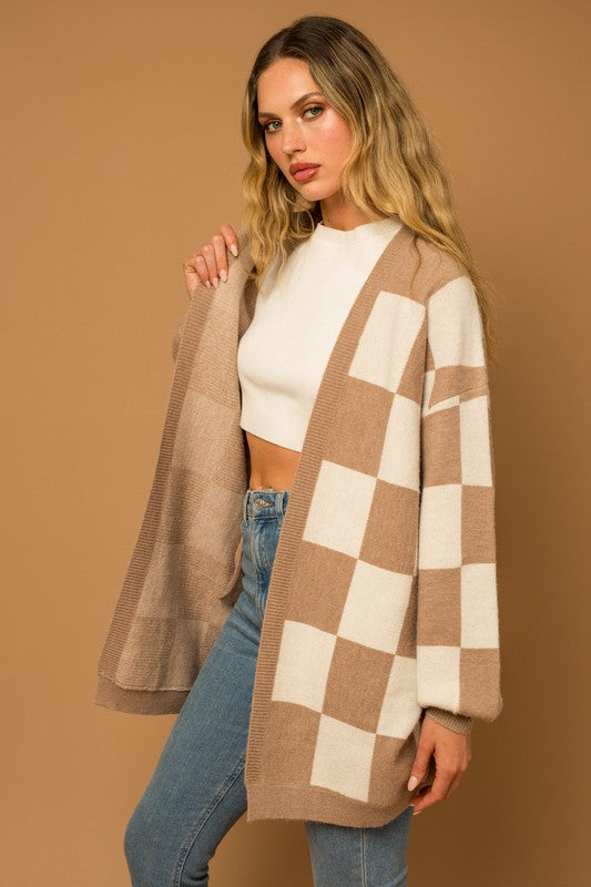 A long open-front cardigan made of knit fabric with a taupe and white checker pattern. It features long sleeves, side pockets, and a relaxed, medium long length