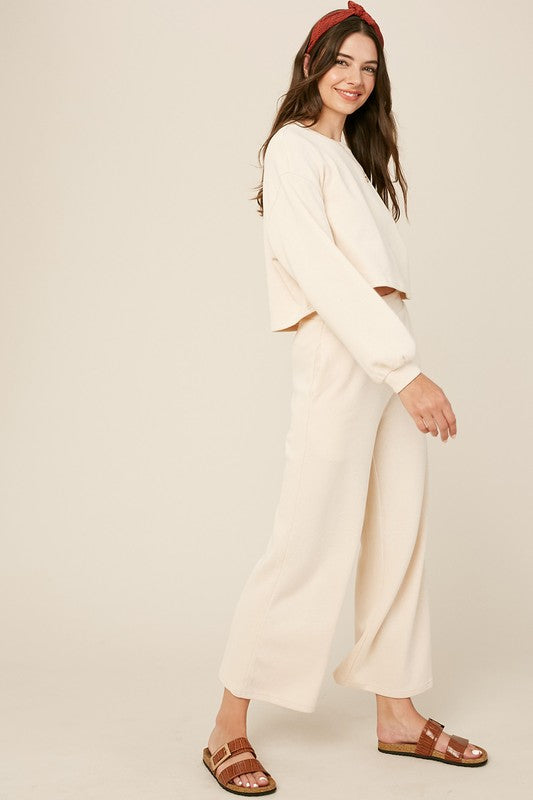 Cozy cream knit sweat top with round neck and long sleeves paired with wide-leg cream pants featuring an elastic waist and pockets.