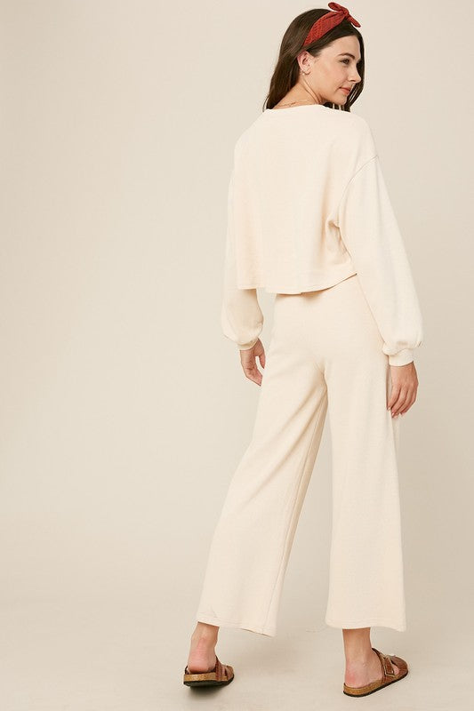 Cozy cream knit sweat top with round neck and long sleeves paired with wide-leg cream pants featuring an elastic waist and pockets.