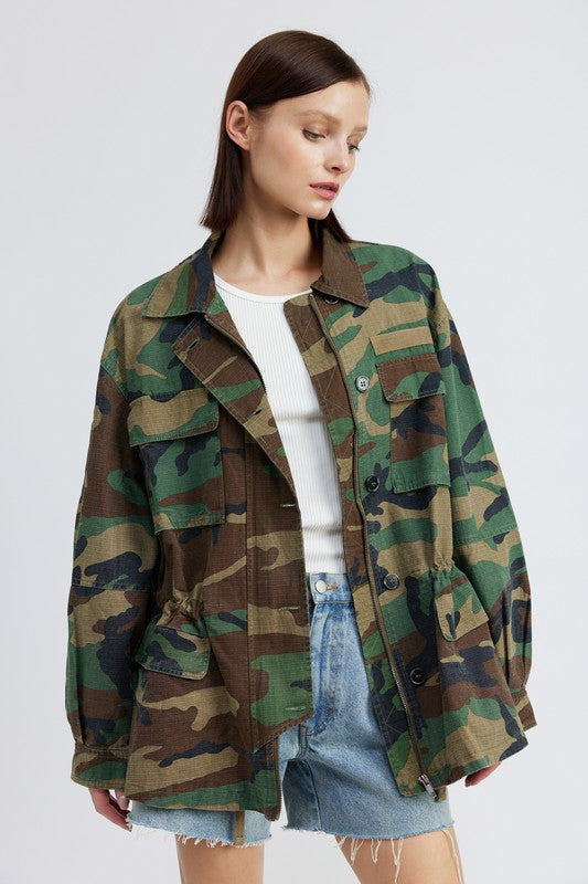 Oversized camo jacket with a collared neckline, long sleeves, and practical pockets. Made of 100% cotton with zipper and button closures.