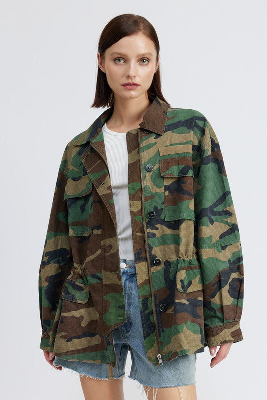 Oversized camo jacket with a collared neckline, long sleeves, and practical pockets. Made of 100% cotton with zipper and button closures.